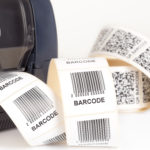 A stream of adhesive labels coming out of a barcode label printer